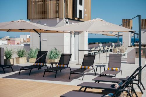 a group of chairs and umbrellas on a patio at Hotel Cetina Cabo de Palos Puerto in Cabo de Palos