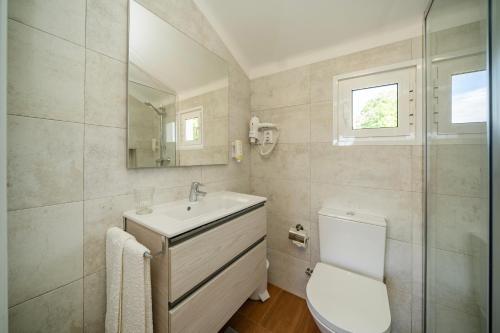 Un baño con lavabo, inodoro y espejo. en Quinta Da Aldeia, en Ponte de Lima