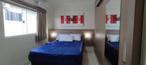 a small bedroom with a blue bed and two windows at Villa Ludovisi Lacqua II in Caldas Novas