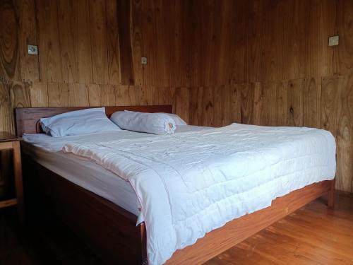 a bed with white sheets and pillows in a room at Noor Homestay Tetebatu in Tetebatu