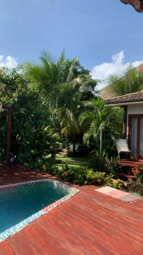 a swimming pool next to a house with palm trees at Barra Suítes in Barra Grande
