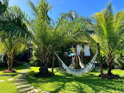 a hammock between palm trees in a yard at Barra Suítes in Barra Grande