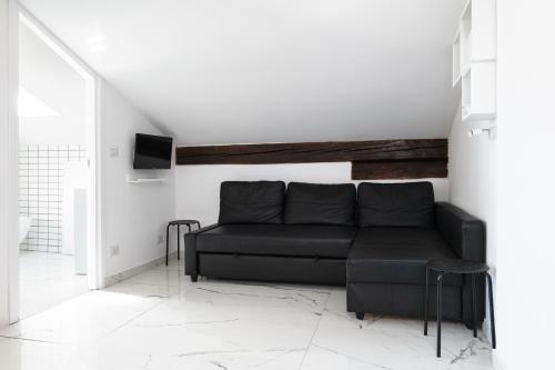 a living room with a black couch and a tv at Saragozza Apartments - Bologna Short Rental in Bologna
