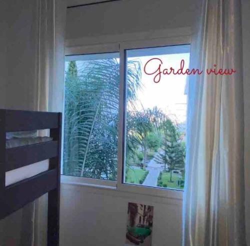 a bedroom window with a view of a palm tree at Moderne appartement met tuin in Tangier