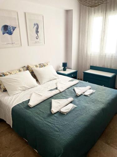 a bed with three pillows and towels on it at Odysseus Boutique Apartment in Ermioni