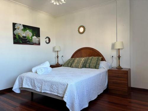 a bedroom with a bed and two lamps and a clock at Desconectaengalicia El Pescador, vistas al puerto, 200m playa in Portonovo