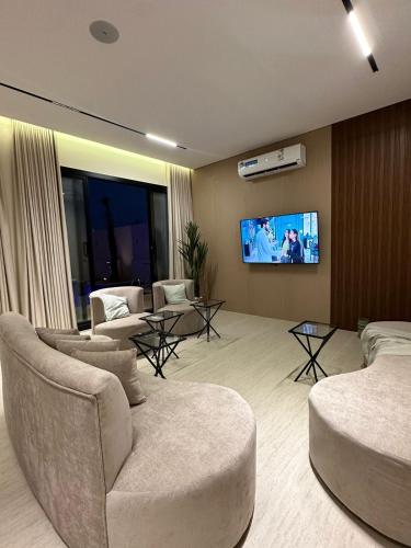 a living room with couches and a flat screen tv at شاليهات رزانه الفندقية in Ilbaras