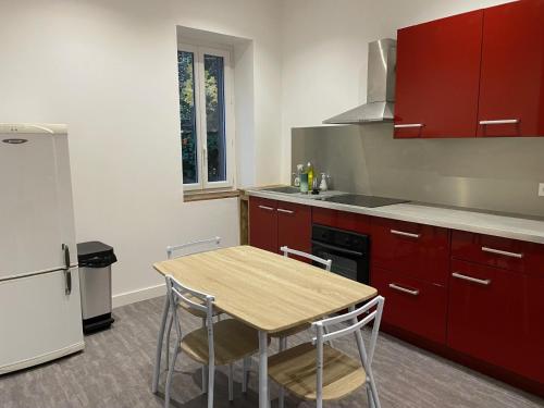 une cuisine avec des placards rouges et une table en bois avec des chaises dans l'établissement 6 couchages proche centre ville location tarif spécial longue durée, à Caluire-et-Cuire