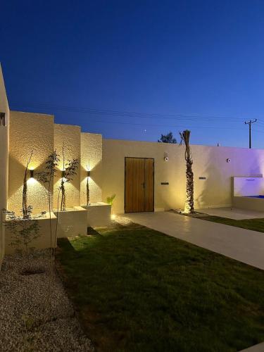 a white building with a door and a palm tree at شاليهات رزانه الفندقية in Ilbaras