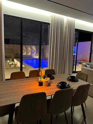 a dining room table with chairs and a large window at شاليهات رزانه الفندقية in Ilbaras