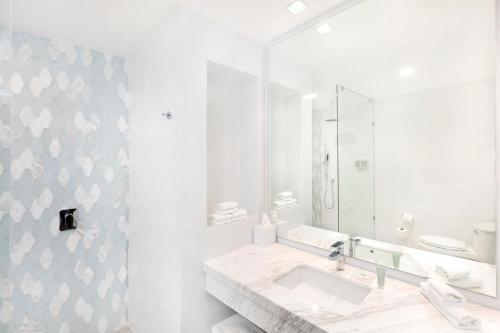 a white bathroom with a sink and a mirror at Courtyard by Marriott Mazatlan Beach Resort in Mazatlán