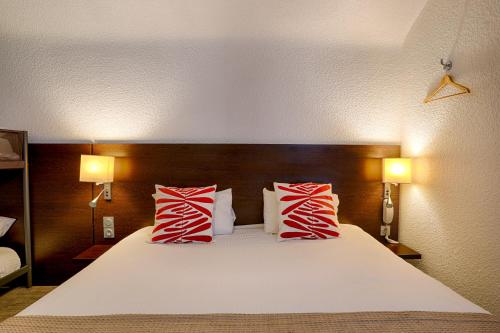 a bedroom with a large bed with red and white pillows at Hotel Le Branhoc - Brit Hotel Auray in Auray