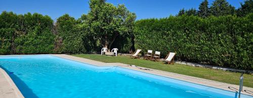 a swimming pool with two lawn chairs and two deck chairs at Quinta de S. Domingos - Viseu in Viseu