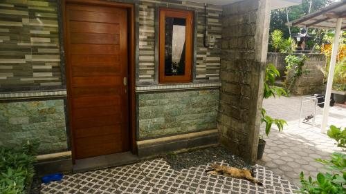 a dog laying on the ground next to a door at Nick Homestay Bali in Uluwatu