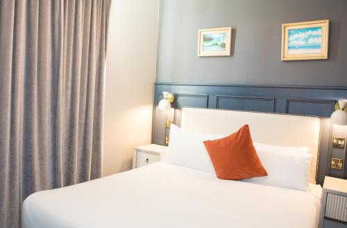 a bedroom with a white bed with an orange pillow at Henrietta House, a member of Radisson Individuals in Bath