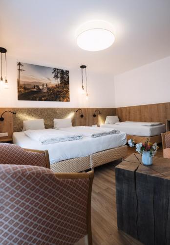 a hotel room with two beds and a table at Hotel Zur Post in Döbriach