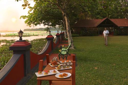 a table with plates of food on it next to a fence at Taj Kumarakom Resort and Spa Kerala in Kumarakom
