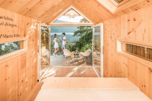 a wooden room with a bed and two people standing on a balcony at Hotel Zur Post in Döbriach