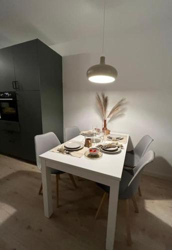 a white dining room table with chairs and a light at Fischer-Chic - Die Bude Maasholm in Maasholm