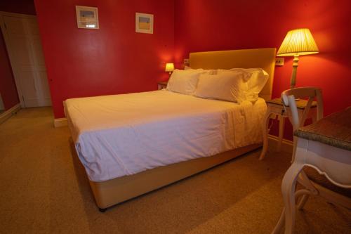 a bedroom with a white bed with a red wall at Buccleuch and Queensberry Arms Hotel in Thornhill