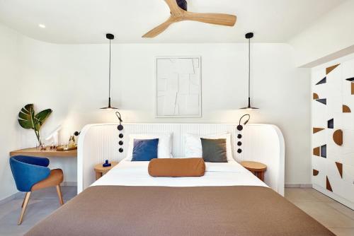 a bedroom with a white bed and a blue chair at Paralos Kosta Alímia in Hersonissos