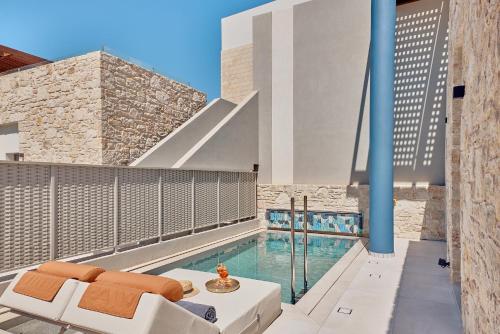a balcony with a swimming pool and a white couch at Paralos Kosta Alímia in Hersonissos