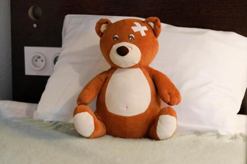 a brown teddy bear sitting on a bed at Hotel Le Branhoc - Brit Hotel Auray in Auray