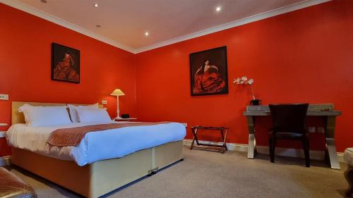 a bedroom with orange walls and a bed and a desk at Buccleuch and Queensberry Arms Hotel in Thornhill