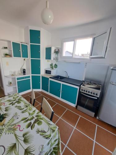 - une cuisine avec des placards verts et blancs, une table et une cuisinière dans l'établissement Maison de ville avec cour et terrasse, à Vichy