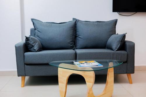 a blue couch with pillows and a glass table at UCHA Hotel & Suites in Kampala