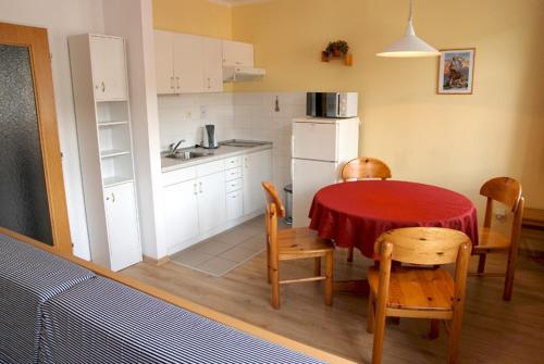 eine Küche mit einem roten Tisch und Stühlen sowie eine Küche mit einem Kühlschrank in der Unterkunft Dolní Náměstí in Rokytnice nad Jizerou