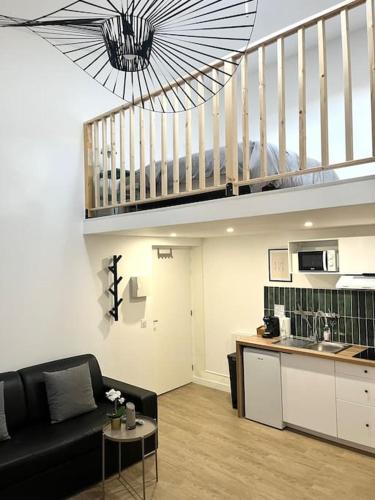 un salon avec un canapé noir et une cuisine dans l'établissement 731 Joli studio mezzanine proche du métro L9, à Bagnolet