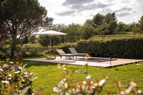 a patio with two chairs and an umbrella in a garden at Coquillade Provence - Relais & Châteaux in Gargas