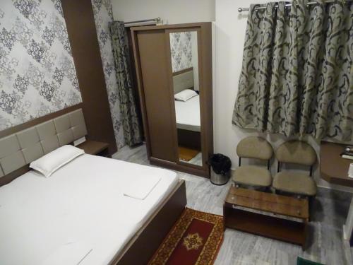 una camera da letto con un letto, uno specchio e una sedia di Hotel Alka a Varanasi