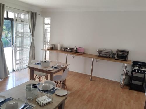 a room with a table and chairs and a kitchen at Paulshof Guesthouse - Kingsway B&B in Sandton