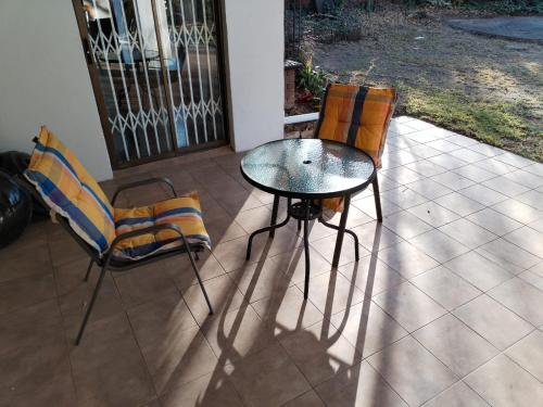 a glass table and two chairs on a patio at Paulshof Guesthouse - Kingsway B&B in Sandton