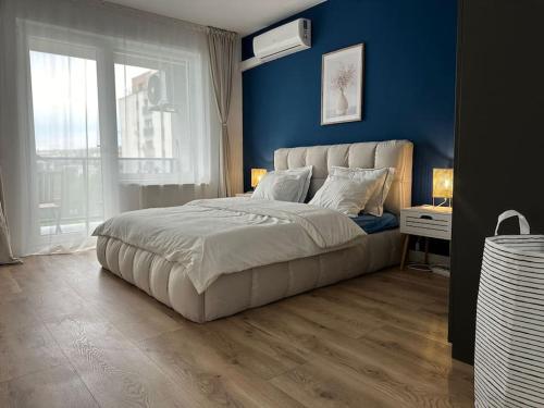 une chambre avec un grand lit avec un mur bleu dans l'établissement home as home, à Cluj-Napoca