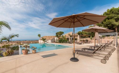 una piscina con sombrillas y sillas y una piscina en Mangiabove, en Marina di Ragusa