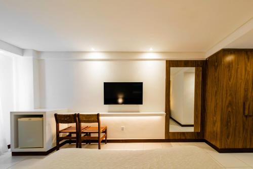 a room with two chairs and a television on a wall at Porto Suítes Natal Hotel in Natal