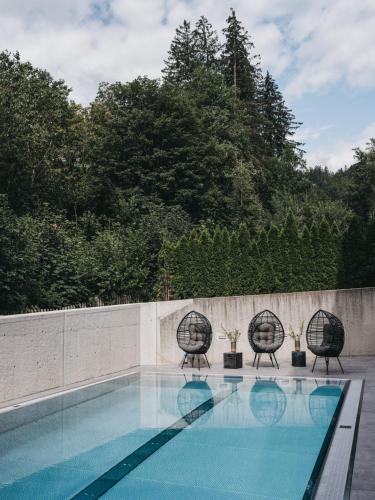 a swimming pool with two chairs and a fence at VAYA Zillertal inklusive Gästekarte Erste Ferienregion Zillertal in Aschau