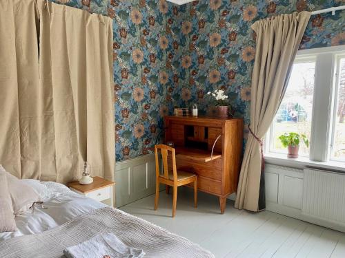 a bedroom with a desk with a chair and a window at Pensionat Kanalvillan in Väddö