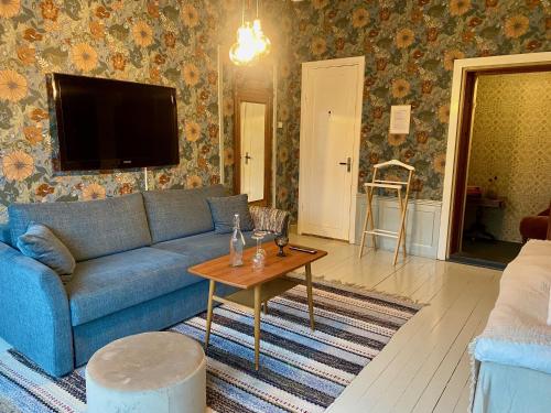 a living room with a blue couch and a table at Pensionat Kanalvillan in Väddö