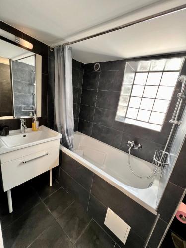 une salle de bain avec une baignoire, un lavabo et une fenêtre dans l'établissement Atelier artiste à 10 de Paris avec terrasse, à Vitry-sur-Seine