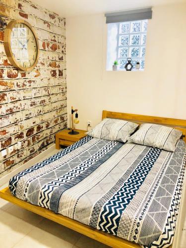 un lit dans une chambre avec une horloge au mur dans l'établissement Atelier artiste à 10 de Paris avec terrasse, à Vitry-sur-Seine