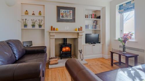 a living room with a couch and a fireplace at Fisherman's Cottage in Somerford Keynes