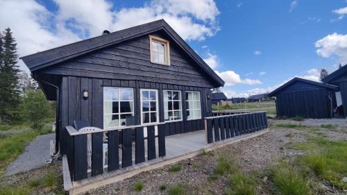 a black tiny house with a wooden deck at Bjørkefinken by Norgesbooking - cabin for hiking and skiing in Tisleidalen
