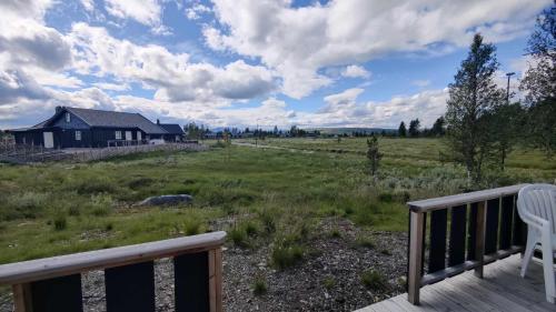 a deck with a chair and a house in a field at Bjørkefinken by Norgesbooking - cabin for hiking and skiing in Tisleidalen