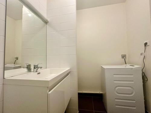 une salle de bain blanche avec un lavabo et un miroir dans l'établissement Le Thémis, cosy et élégant, à Limoges