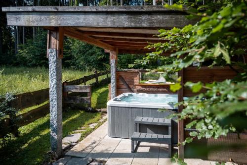 a hot tub sitting under a wooden pergola at Bayern Chalets bei Salzburg und Berchtesgaden mit Whirlpool und Sauna in Ainring