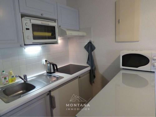 une petite cuisine avec un évier et un micro-ondes dans l'établissement Studio Confortable avec Coin Montagne et Garage - 4 Pers - Le Grand-Bornand - FR-1-458-190, au Grand-Bornand